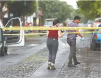  ??  ?? En medio de la lluvia, peritos trabajan en el levantamie­nto de los cuerpos de dos hombres asesinados con arma de fuego en Colima.