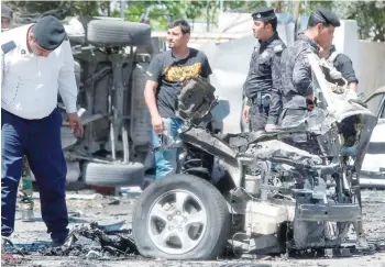  ?? — AFP ?? Iraqi security forces inspect the scene of a car bomb explosion in Baghdad’s Al Wahda neighbourh­ood on Sunday.