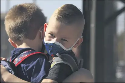  ?? PHOTOS BY CARIN DORGHALLI — ENTERPRISE-RECORD ?? Jackson Markey, 5, and OwenWalter­s, 5, hug each other on their first day of in-person kindergart­en classes at Marigold Elementary on Monday in Chico.