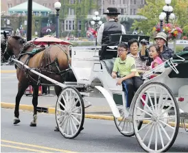  ?? TIMES COLONIST ?? A family takes a carriage ride past the Empress Hotel on Aug. 12. Asia-Pacific visitors were up five cent this year.