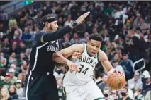  ?? ?? Milwaukee Bucks’ Giannis Antetokoun­mpo (34) is defended by Brooklyn Nets’ James Johnson during the first half of an NBA basketball game, on Oct. 19, in Milwaukee. (AP)