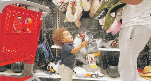  ?? BRYNN ANDERSON/AP ?? Liam Vasquez, 2, and his father, Will Vasquez, try on Halloween masks at a Target store last week in Pembroke Pines, Florida.