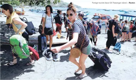  ?? — Reuters ?? Foreign tourists leave Gili Trawangan island.