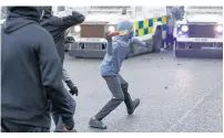  ?? Photo / AP ?? A Nationalis­t youth throws a molotov cocktail at a police line blocking a road near the Peace Wall in West Belfast.