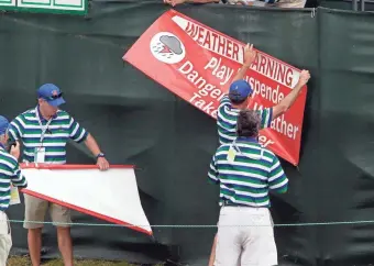  ??  ?? Officials put up suspended play signs Wednesday at the U.S. Open at Erin Hills.