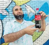  ?? GERRY KAHRMANN/PNG ?? Zahid Mahmood, owner of the Hasty Market and Snack Land store, holds a bottle of Coca-Cola bearing the tag line ‘Missing You.’