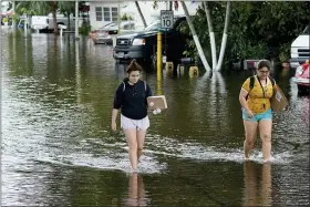 ??  ?? Victoria Rodriguez, left, and Angela Mojica, right, walk on a flooded street in the Driftwood Acres Mobile Home Park, in the aftermath of Tropical Storm Eta, Nov. 10, in Davie, Fla.