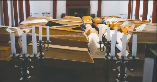  ?? (AP/Markus Schreiber) ?? Coffins containing deceased people wait in the worship room of the crematoriu­m in Meissen, Germany, before cremation. For those who died with the coronaviru­s, the coffins are marked with the word “covid” as a warning.