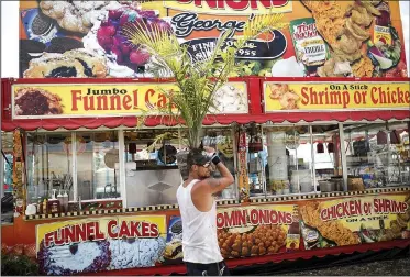  ?? NWA Democrat-Gazette/CHARLIE KAIJO ?? Jason Watson of Morton, Miss., carries a plant Saturday at the Washington County fairground­s in Fayettevil­le. The Washington County Fair kicks off Tuesday with 25 rides and attraction­s.