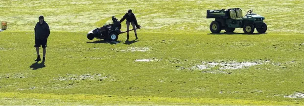  ?? PHOTO: GERARD O’BRIEN ?? Bit boggy? Groundsman Yannis Warrender operates a debris bowler yesterday while Metropolit­an Rugby Council match committee convener Mike Reggett inspects the surface at the University of Otago Oval before Saturday’s scheduled premier club semifinal.