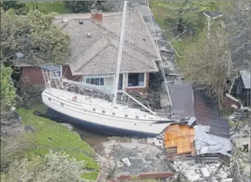  ?? Steve Helber / Associated Press ?? A sailboat is shoved up against a house and a collapsed garage Saturday after heavy wind and rain from florence blew through new Bern, n.c.