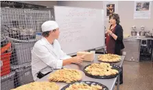  ?? JIM THOMPSON/JOURNAL ?? Austin Fenner, an aspiring chef, gets some early practice in a new West Mesa High culinary arts lab. At right is APS Superinten­dent Raquel Reedy.