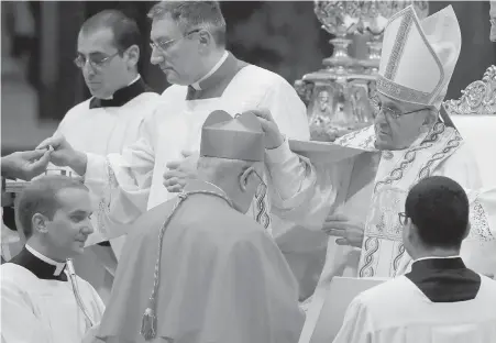  ??  ?? New Cardinal Pedro Barreto receives the three-cornered biretta hat from Pope Francis in St. Peter’s Basilica at the Vatican on Thursday.