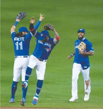  ?? GREGORY FISHER / USA TODAY SPORTS FILES ?? Toronto Blue Jays infielders Bo Bichette and Jonathan Villar, with outfielder Teoscar Hernandez, celebrate a victory
over the New York Yankees Sept. 24 at Buffalo's Sahlen Field — clinching the team's first playoff spot since 2016.