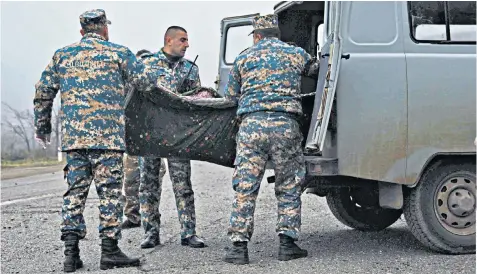  ??  ?? Soldiers load a body on to a vehicle on the battlefiel­d in Nagorno-karabakh after Azerbaijan and Armenia signed a peace deal