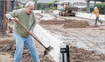  ?? Irfan Khan Los Angeles Times ?? RICHARD WALKER clears mud that accumulate­d on his driveway in Duarte. The city had erected wood and concrete barriers to protect neighborho­ods after wildfires last summer put the area at risk for mudslides.