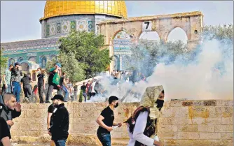  ?? AFP ?? Palestinia­n protesters run for cover from tear gas fired by Israeli cops amid clashes at Jerusalem’s Al-aqsa mosque complex.