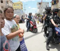  ?? AFP file ?? Residents watch as police team ride past after an anti-drug and criminalit­y raid at an informal settlers area in Manila. —