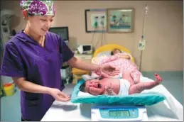  ?? WANG WEIQIAN / XINHUA ?? A midwife weighs a newborn baby at a hospital in Shijiazhua­ng, capital of Hebei province, on Feb 26.