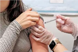  ??  ?? A young woman receives a flu shot. AFP / Justin Sullivan