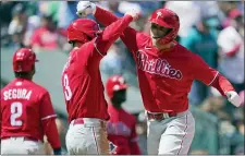  ?? TED S. WARREN — THE ASSOCIATED PRESS ?? Phillies’ Rhys Hoskins, right, is greeted by Bryce Harper, center, at the plate after Hoskins hit a grand slam against the Seattle Mariners on Wednesday.