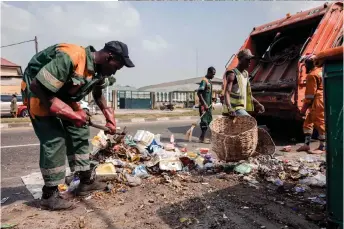  ?? ?? Lagos State Waste Management Authority (LAWMA) staff cleans up piled up waste from the road side at Ikoyi in Lagos.