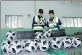  ?? GUAN YUE / FOR CHINA DAILY ?? Customs officials in Guangzhou examine soccer balls suspected of infringing the copyright of the FIFA World Cup.