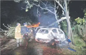  ??  ?? Un agente policial y un bombero revisan la zona del accidente luego de haber apagado las llamas.