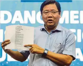  ?? PIC BY SHAHNAZ FAZLIE SHAHRIZAL ?? State Barisan Nasional chairman Teng Chang Yeow showing a copy of a newspaper article on Consortium Zenith BUCG’s announceme­nt in George Town yesterday.