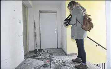  ?? CLAUDE PARIS / AP ?? A video-journalist films the wreckage of an entrance of an apartment building after a raid of a French anti-terrorist police unit in Clapiers in southern France on Friday.