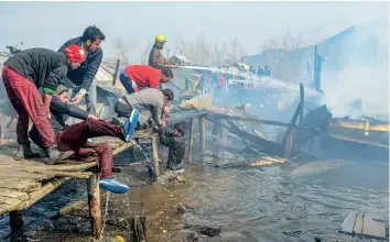  ?? — PTI ?? Fire-fighting personnel and locals attempt to douse a fire in houseboats at KoniKhan, Dal Lake, in Srinagar on Monday. Three houseboats were gutted in the fire.