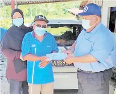  ??  ?? Dr Shahrizin (right) handing over the assistance to fire victim Bahuddin.