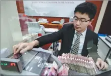  ?? ZHANG YUN / CHINA NEWS SERVICE ?? A teller counts cash at a bank in Taiyuan, Shanxi province.