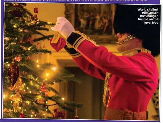  ??  ?? World’s tallest elf: Captain Ross hangs a bauble on the royal tree