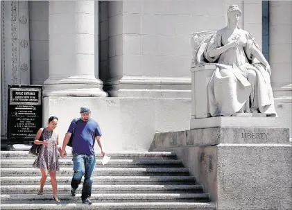  ?? JIM WEBER/THE COMMERCIAL APPEAL ?? Annie Chaleunsak (left) and Steven Coughlin pass by the Liberty statue on their way out of the Shelby County Courthouse. The County Commission voted to rename the building in honor of late Circuit Court Judge D’Army Bailey.