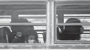  ?? Photos by Jerry Lara / Staff photograph­er ?? A young girl peers out of a bus carrying migrants to a Brownsvill­e bus station last month. The migrants were released by federal authoritie­s after entering the U.S. earlier in February.