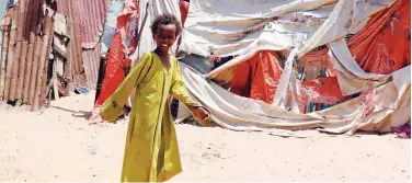  ?? Reuters ?? ↑
A girl walks in front of a makeshift shelter at the Shabelow camp in Mogadishu on Wednesday.