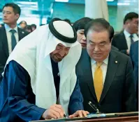  ?? Wam ?? Sheikh Mohamed bin Zayed signs a visitors’ book at National Assembly of South Korea as Moon Hee-sang looks on. —