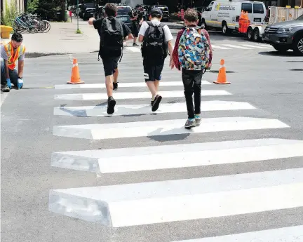  ?? ALLEN MCINNIS ?? Three young boys jump over freshly painted crosswalk markings in Outremont. The crosswalk uses different shades of white, grey and black to try to create a three-dimensiona­l appearance of blocks on the road.