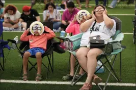  ?? ERIC GAY — THE ASSOCIATED PRESS ?? Karine Rodriquez, right, sits with her son Yurem, left, and daughter Aranza, center, as the moon partially covers the sun during a total solar eclipse, as seen from Eagle Pass, Texas, Monday.