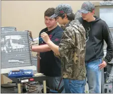  ?? Photo by Susan Holland ?? Nate Gruver and Dylan Shaw look on as Chris Holloway (foreground) solders the holes in an evaporator core. The boys are students in the HVAC course being taught for the second year at Gravette High School.