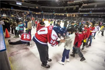  ?? Herald photo by Tijana Martin @TMartinHer­ald ?? Lethbridge Hurricanes player Jake Elmer, centre, signs the sweater of a young AMA school safety patroller, while Keltie JeriLeon gets on the ice to sign a pair of skates during the AMA Lethbridge Hurricanes and School Safety Patrol Skate Day at the...