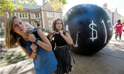  ?? Photograph: Paul J Richards/AFP/Getty Images ?? Students pull a mock ball and chain representi­ng student debt, at Washington University in St Louis, Missouri.