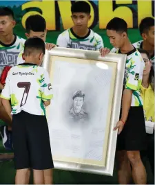  ??  ?? Above: The Thai boys and their football coach attend a press conference in Chiang Rai following their discharge from the hospital. Left: The boys show their respect with a portrait of diver Saman Gunan, who died during the rescue. Far left: Coach Ekkapol Chantawong, known as Ake, greets a wellwisher at the event. Photos: Getty