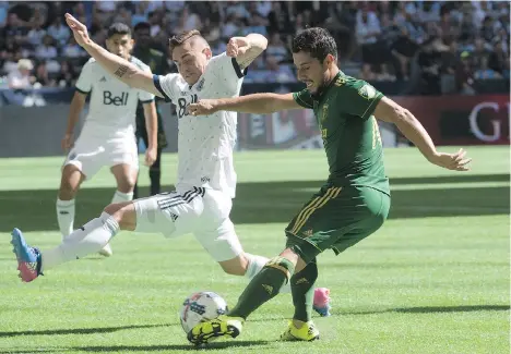  ?? JONATHAN HAYWARD/THE CANADIAN PRESS ?? Vancouver Whitecaps defender Jake Nerwinski, left, fights for control of the ball with Portland Timbers midfielder Sebastian Blanco, right, during the first half at B.C. Place Stadium on Sunday. Blanco scored the deciding goal as the Timbers won 2-1.