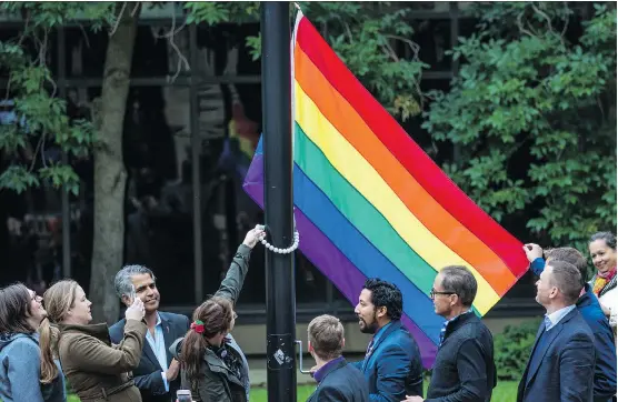  ?? PHOTOS: GAVIN YOUNG ?? Government MLAs and guests celebrate Pride Week with the raising of a Pride flag outside the McDougall Centre on Monday.