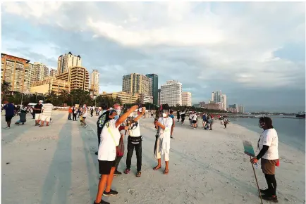  ?? PHILIPPINE STAR / MIGUEL DE GUZMAN ?? PEOPLE gather at the artificial white sand beach along the shore of Manila Bay.