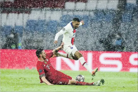  ?? MATTHIAS SCHRADER / AP ?? Kylian Mbappé intenta superar la oposición de Süle, bajo la nieve en Munich