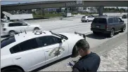  ?? CHRIS CARLSON—ASSOCIATED PRESS ?? In this April 23, 2021file photo, California Highway Patrol officer Troy Christense­n runs a driver’s license after stopping a motorist along Interstate 5who was suspected of speeding in Anaheim, Calif. The number of highway deaths in 2020was the greatest in more than a decade even though cars and trucks drove fewer miles during the pandemic, and motorists are continuing to speed, tailgate and zigzag through traffic.