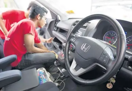  ?? LIM HUEY TENG/ASSOCIATED PRESS ?? Honda technician­s work on a car at a free air bag replacemen­t event Nov. 16 in Kuala Lumpur, Malaysia. Honda just added 772,000 cars to its recall.